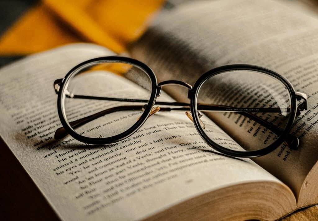 Artistic close-up of round eyeglasses on an open book, perfect for literary or reading themes.